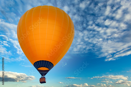 Orange aerostat against the blue sky with white clouds, sharpness on the ball, used as a background