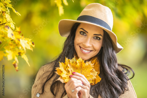 Gorgeous female holding fallen colorful leaves in her hands out in the park