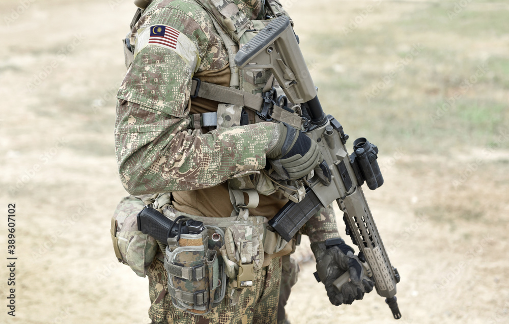 Fototapeta premium Soldier with assault rifle and flag of Malaysia on military uniform. Collage.