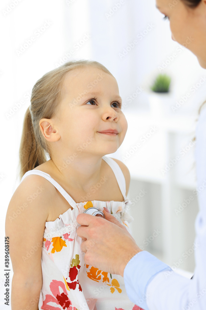 Doctor examining a little girl by stethoscope. Happy smiling child patient at usual medical inspection. Medicine and healthcare concepts Doctor examining a little girl by stethoscope. Happy smiling child patient at usual medical inspection. Medicine and healthcare concepts