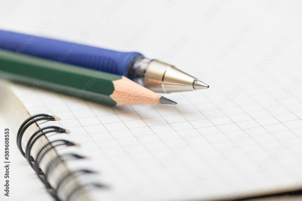 Pen and lead pencil on blank page of the notebook. Selective focus with short DOF. Close up view. Pen and lead pencil on blank page of the notebook. Selective focus with short DOF. Close up view.