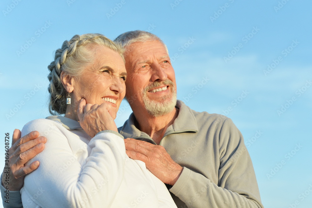 Happy senior couple hugging against blue sky