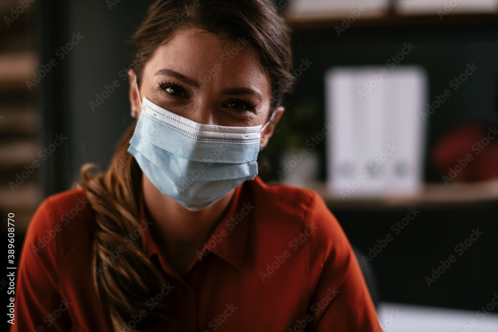 Beautiful businesswoman with medical mask working in office. Young businesswoman working on lap top.