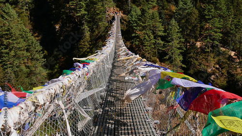 Colorful Buddhist prayer flags peacefully flying in the wind on popular Hillary Suspension Bridge on the way up to Namche Bazar, Himalayas, Nepal on Everest Base Camp Trek.