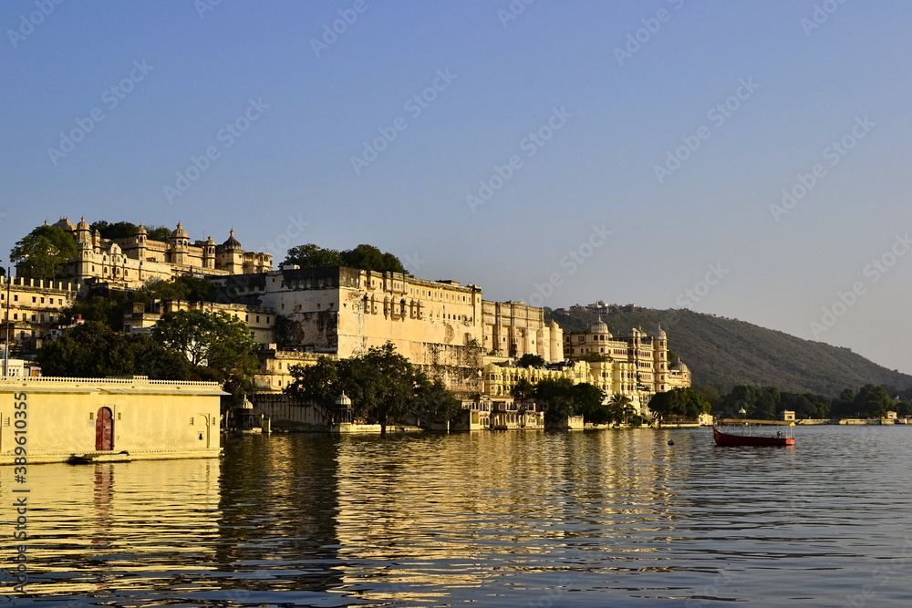 View the Udaipur City Palace reflecting in a water of Pichola Lake. Sunset time. Udaipur also known as the City of Lakes
