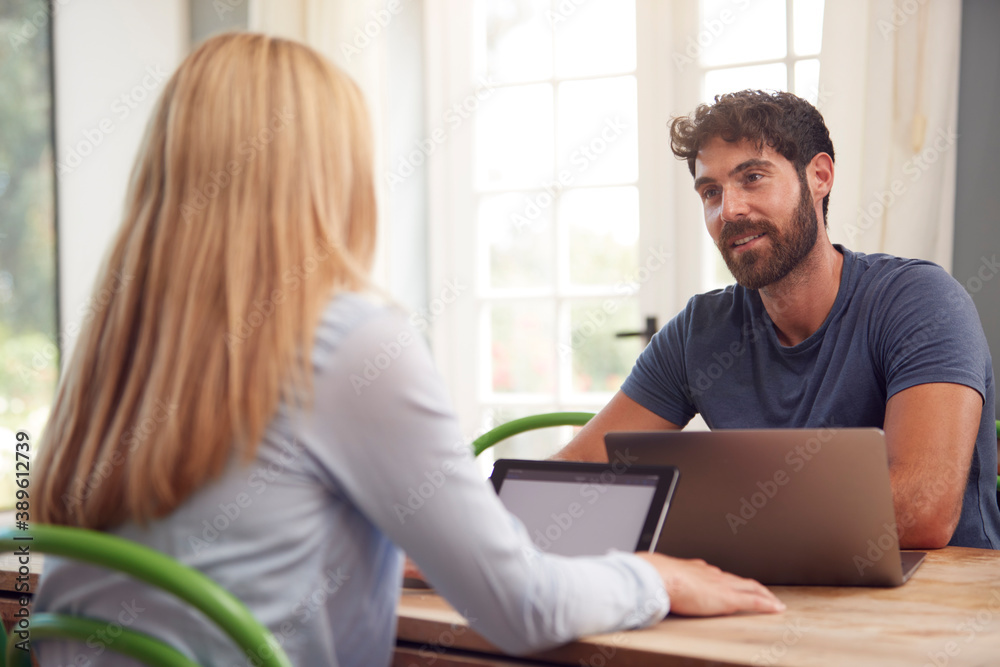 Couple With Laptop Sitting At Table Working From Home Together Couple With Laptop Sitting At Table Working From Home Together