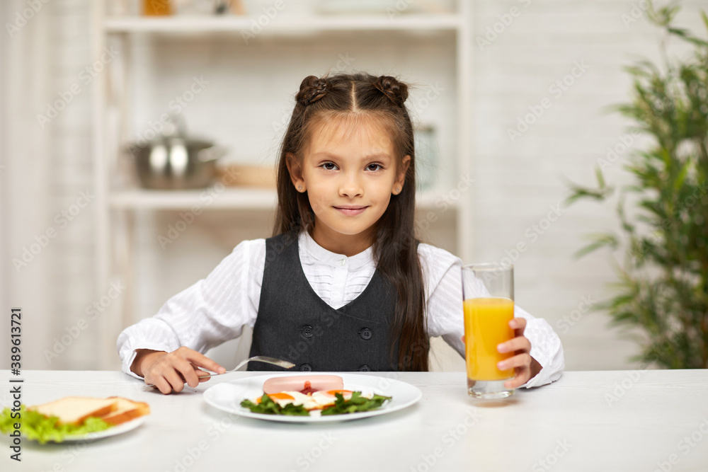 little child girl having breakfast - fried egg and orange juice in the kitchen. healthy breakfast. fried egg face smiles on a white plate little child girl having breakfast - fried egg and orange juice in the kitchen. healthy breakfast. fried egg face smiles on a white plate