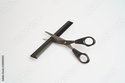 stainless steel scissors with black handle lie and comb on a light table