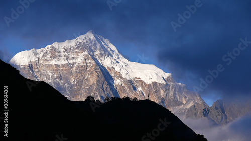 Stunning view of majestic mountain Taboche (peak 6,501 m) looking through the clouds with silhouette of a hill in foreground from Mount Everest Viewpoint, Namche Bazar, Khumbu, Himalayas, Nepal.