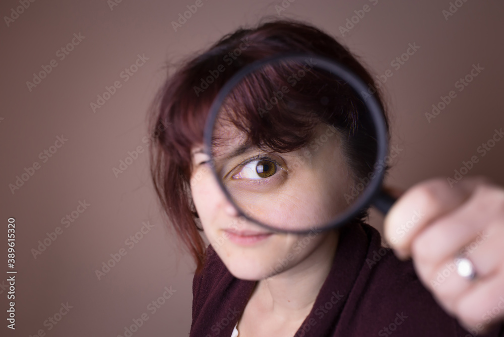 Woman looking through magnifying glass, loop. Questioning things