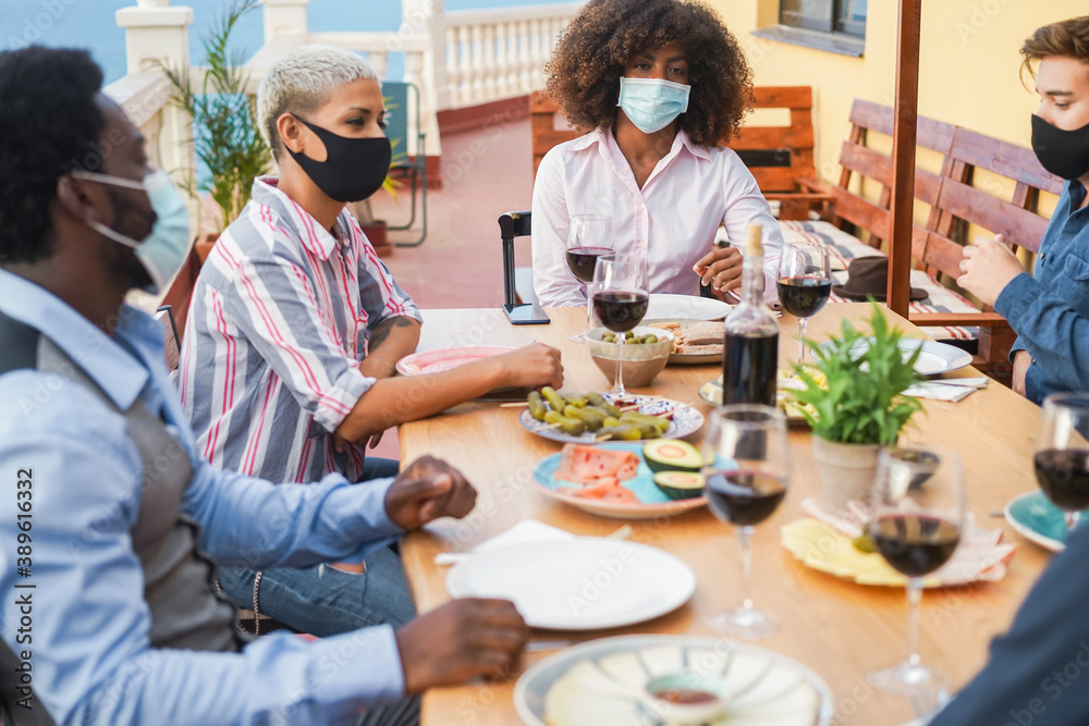 Young multiracial people eating and drinking together while wearing face protective masks - Focus on black girl - obrazy, fototapety, plakaty 
