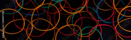 bright colorful stationery rubber bands on black background, close view . High quality photo