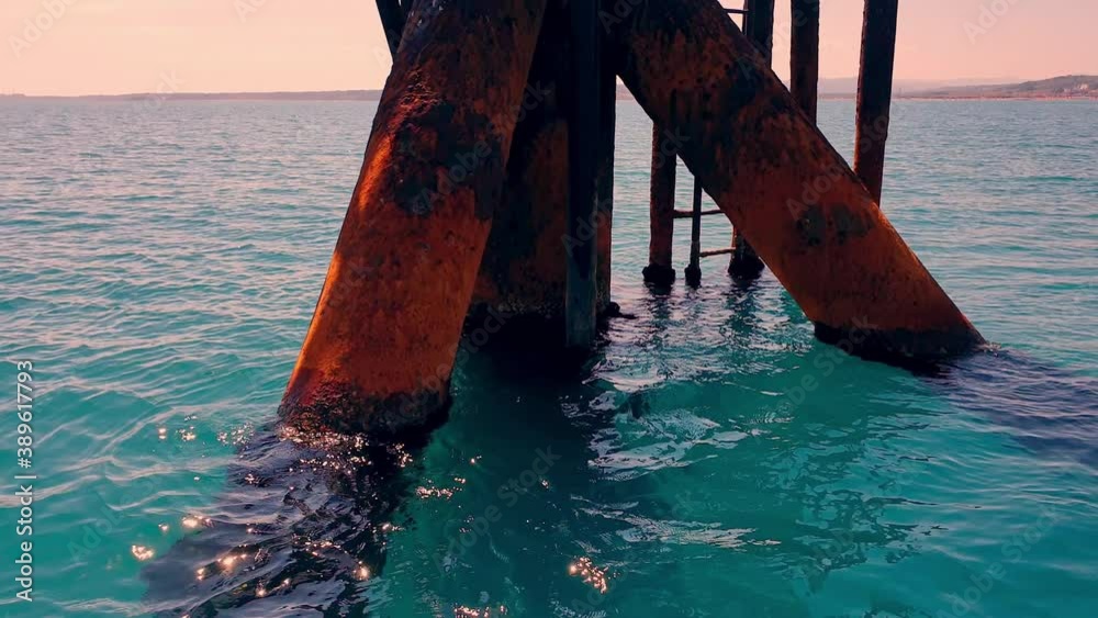 Circling view of offshore oil platform or oil rig pylons in open sea