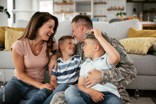 Happy soldier sitting on the floor with his family. Soldier and his wife enjoying at home with children