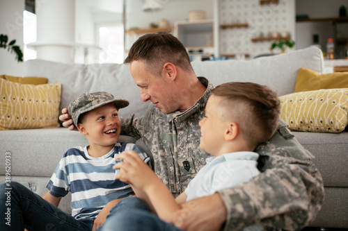 Happy soldier sitting on the floor with his family. Soldier enjoying at home with children.