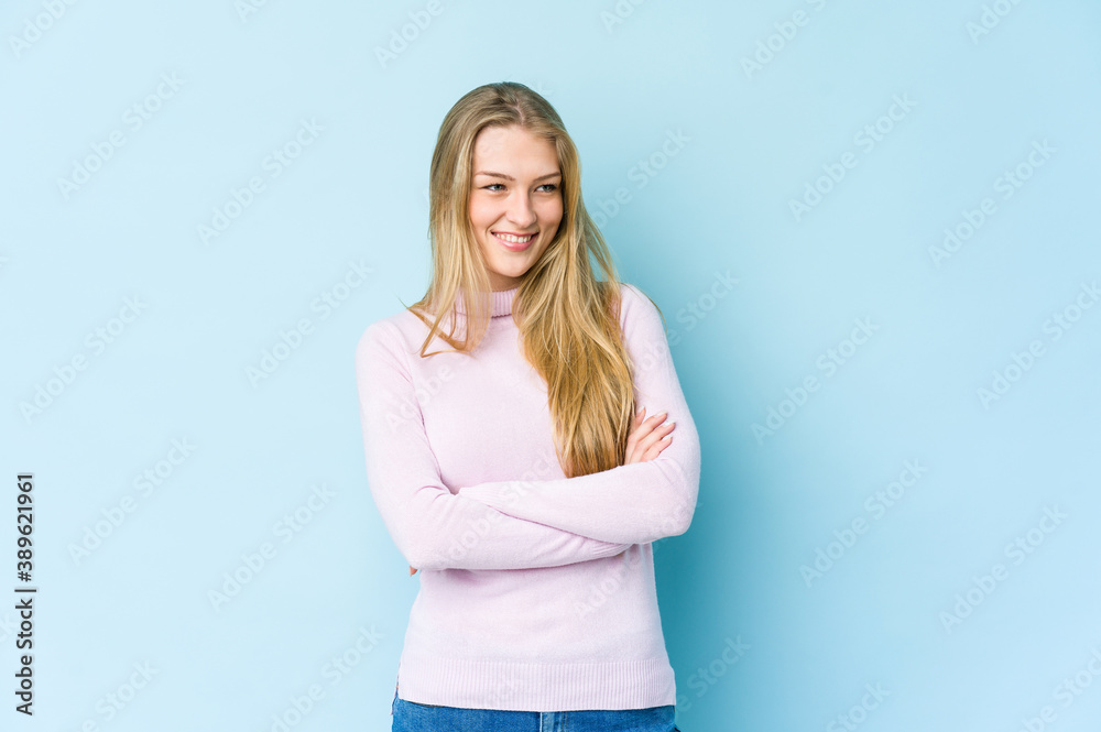 Young blonde woman isolated on blue background smiling confident with crossed arms. Young blonde woman isolated on blue background smiling confident with crossed arms.