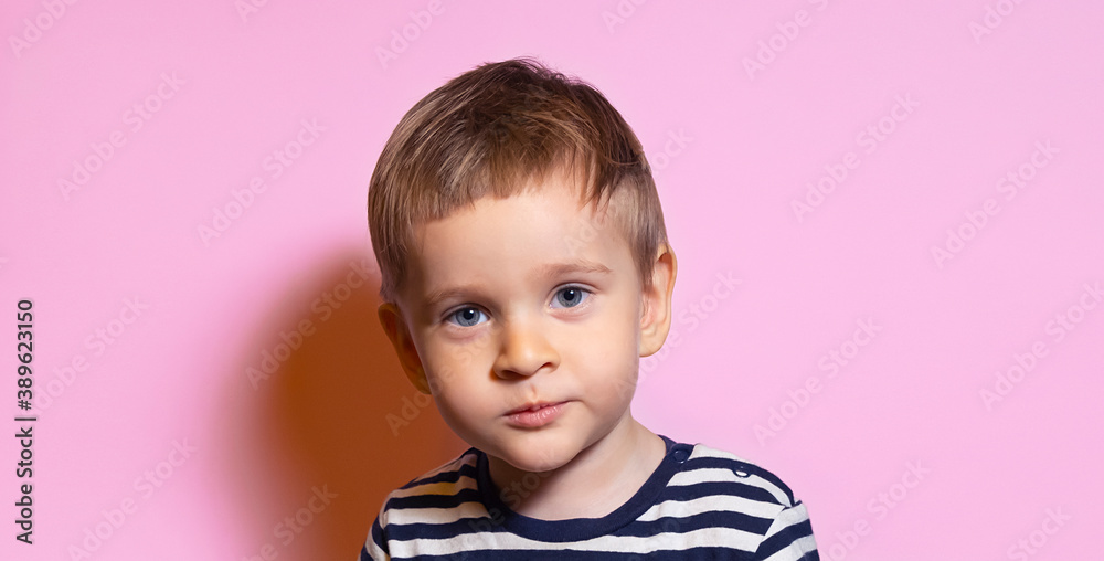 blond boy in striped t-shirt on a pink background
