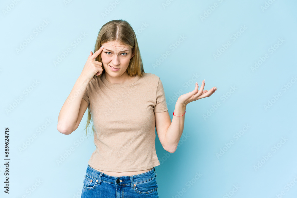 Young blonde woman isolated on blue background showing a disappointment gesture with forefinger. Young blonde woman isolated on blue background showing a disappointment gesture with forefinger.