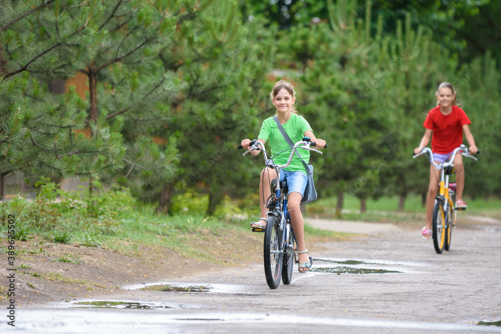 Two girls ride a bike on a rainy warm day