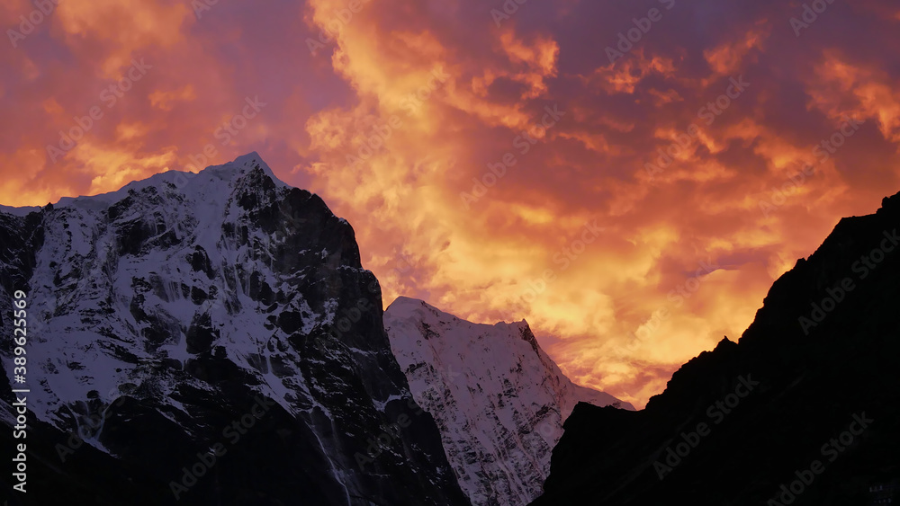 Stunning sunset above ice-capped mountains in the Himalayas near village Thame, Khumbu, Nepal with dramatic colorful sky looking like the flames of a giant fire.