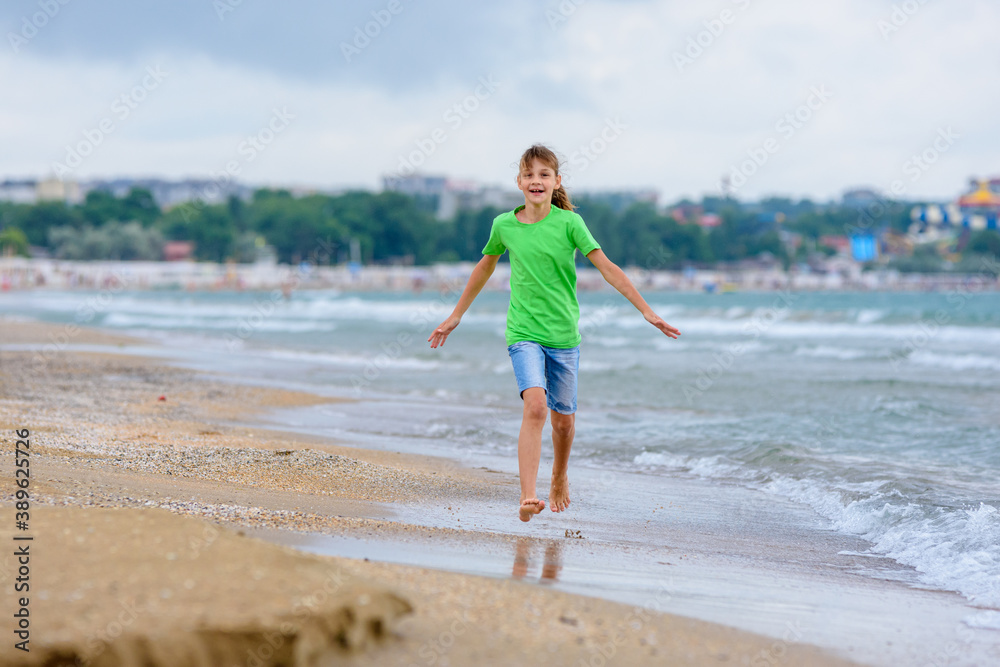 The girl runs happily along the sea coast