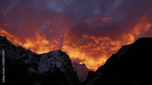 Spectacular sunset over snow-capped mountains in the Himalayas near Sherpa village Thame, Khumbu, Nepal with dramatic orange and purple colored sky looking like the flames of a giant fire.