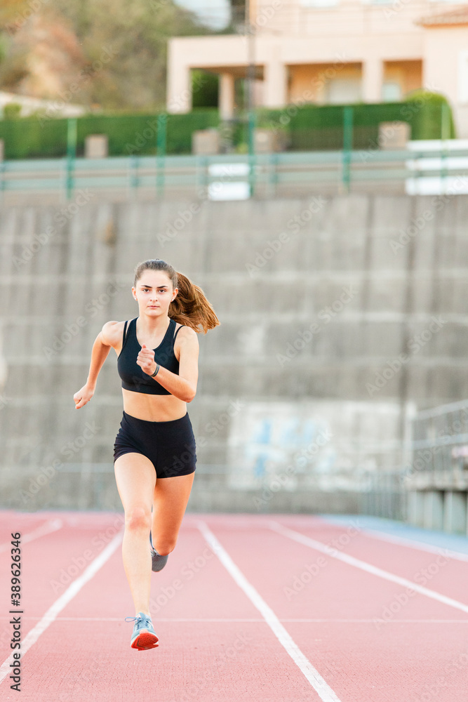 Smiling fit female teenager athlete training on running track