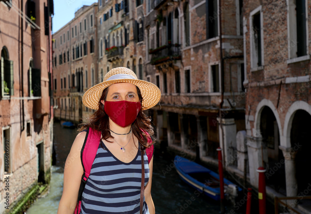 young woman with mask and straw hat while visiting Venice during