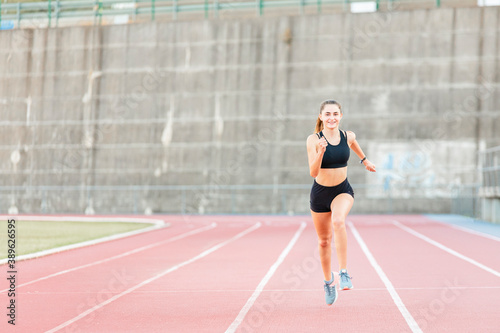 Smiling fit female teenager athlete training on running track © Jake Go