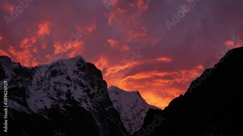 Dramatic sunset with purple and orange colored clouds in the Himalayas with snow-capped craggy mountains near sherpa village Thame, Khumbu region, Nepal on Three Passes Trek.