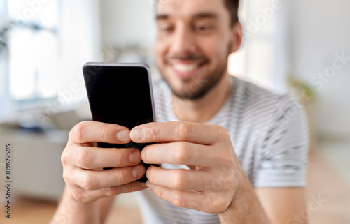 technology, remote job and people concept - close up of happy smiling man with smartphone g at home