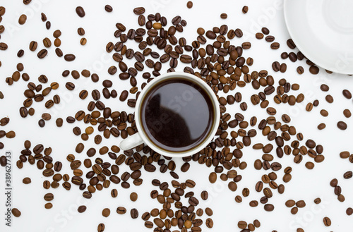 White Cup and saucer with coffee and coffee beans. Top view, white background. Free space for text.