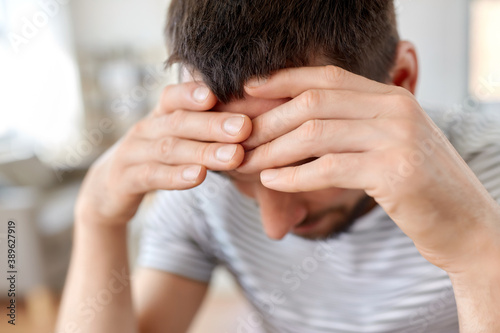 stress, failure and people concept - close up of stressed young man having headache at home