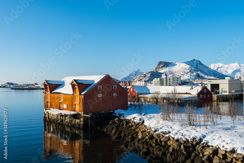 Old traditional fisher hut called Rorbu near Svolvaer on the Lofoten islands in Norway in winter with snow on clear day with blue sky