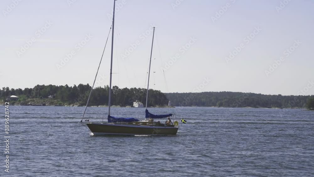 A motor and sailing boat passing the bay of Lillsved on the island Värmdö in Stockholm archipelago a sunny summer day A motor and sailing boat passing the bay of Lillsved on the island Värmdö in Stockholm archipelago a sunny summer day