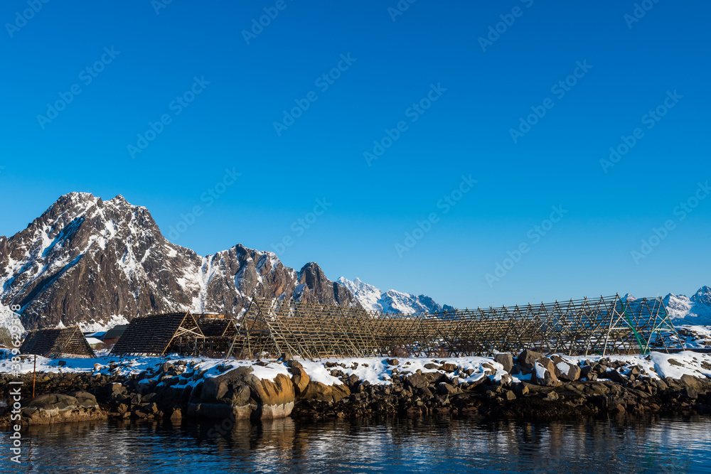 Giant empty wooden racks for hanging and drying cod to make stockfish on the Lofoten islands in Norway on clear winter day with blue sky