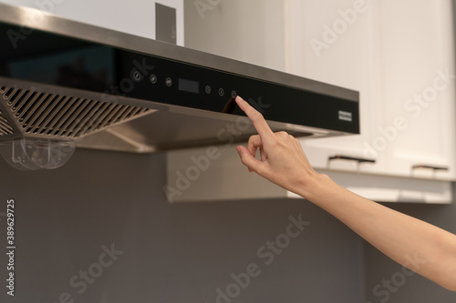 Woman hand opens kitchen hood for cooking. Modern interior.