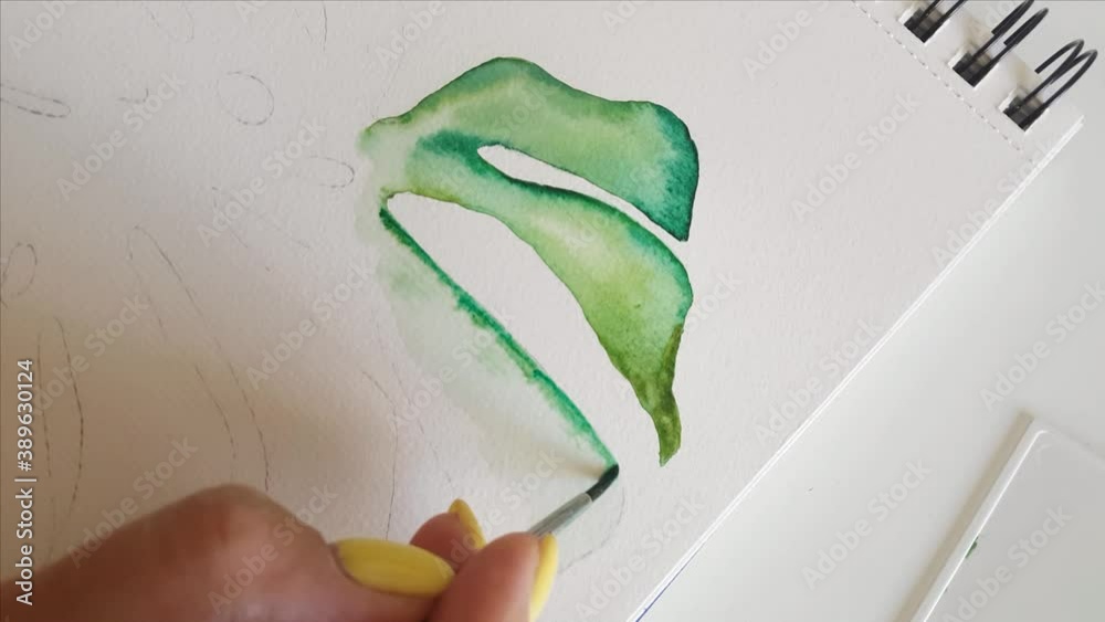 Woman painting Monstera leaf with Watercolors close up