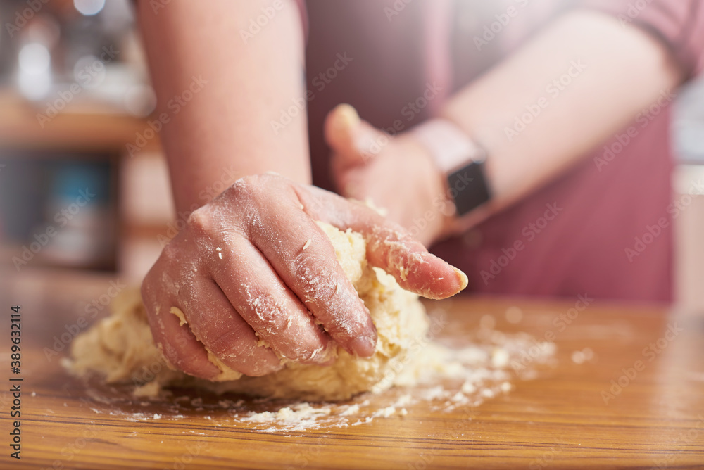 Close up of female hands kneading raw dough at home
