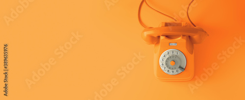 An orange vintage dial telephone with orange background.