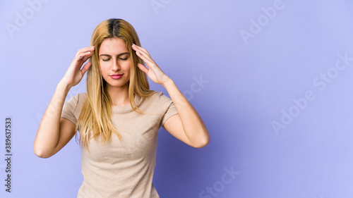 Young blonde caucasian woman touching temples and having headache.