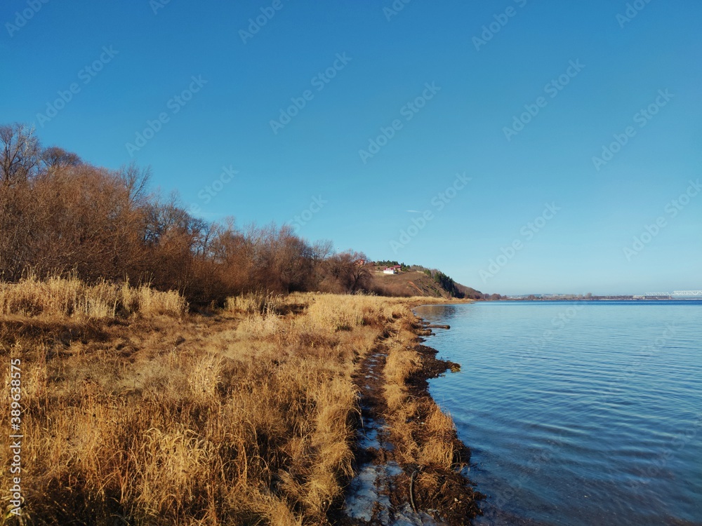 sunny autumn landscape on the river coastline against the blue sky