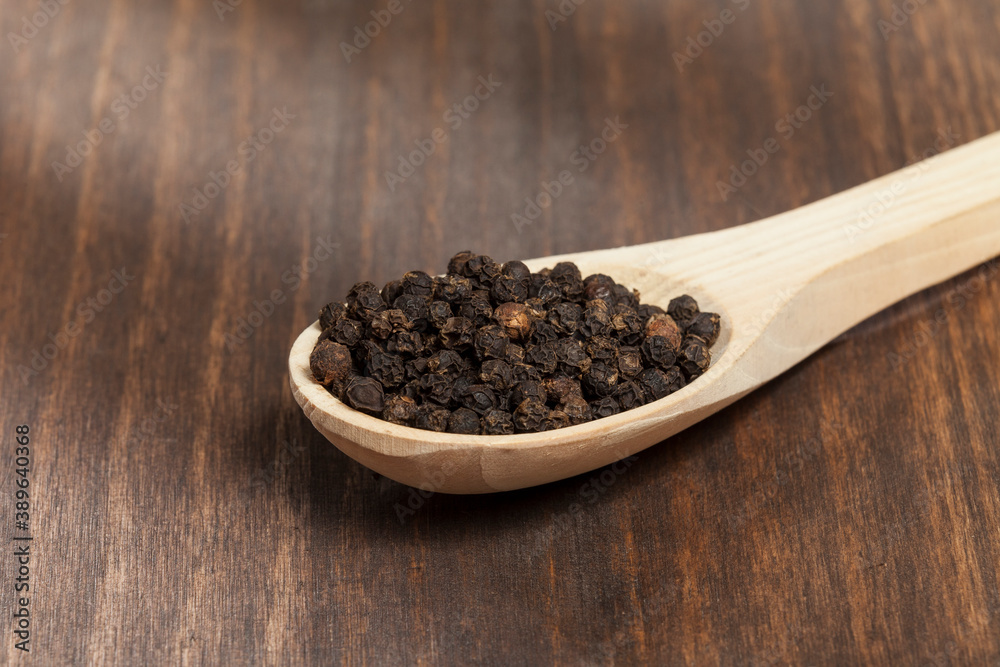 Piper nigrum - black peppercorns; photo on dark wooden background. Piper nigrum - black peppercorns; photo on dark wooden background.