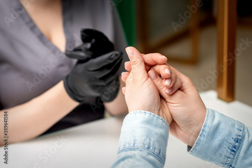 Young woman is rubbing her hands with manicure master in manicure salon