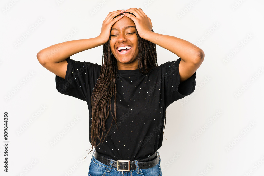 Young african american woman isolated on white background laughs joyfully keeping hands on head. Happiness concept. Young african american woman isolated on white background laughs joyfully keeping hands on head. Happiness concept.