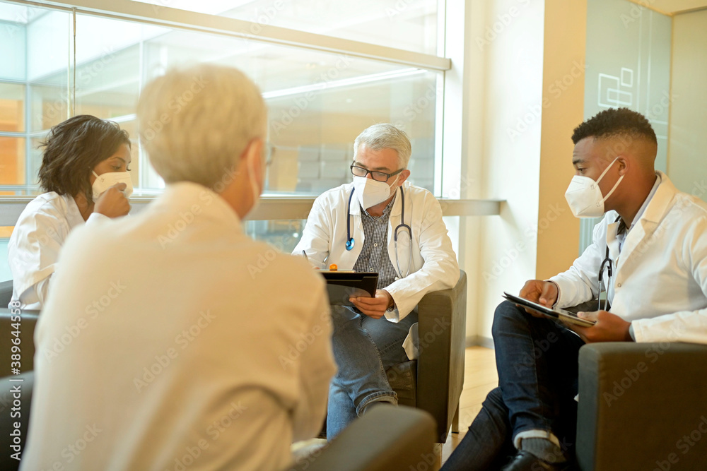 Medical people sitting in meeting room, checking planning together during pandemic Medical people sitting in meeting room, checking planning together during pandemic