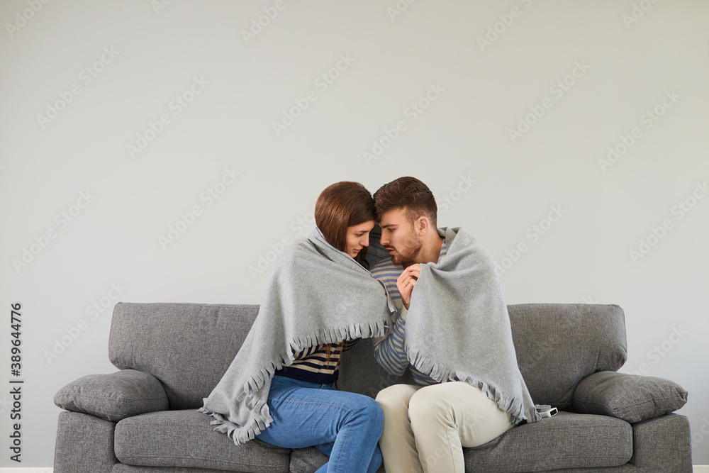 Freezing couple in cool room cuddling in plaid