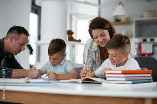 Parents helping the kids with their homework. Litlle boys learning at home..
