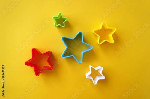 Plastic molds of multi colors for making cookies in the shape of a star on a yellow background.