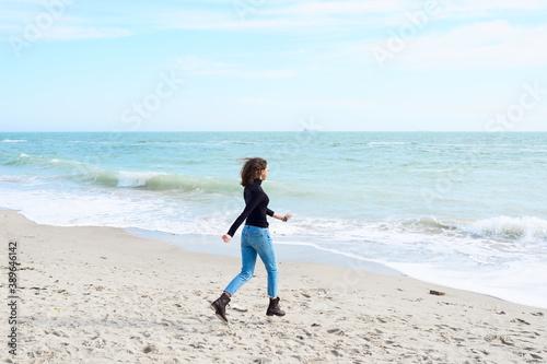 Young woman with dark hair alone relaxing at the sea shore.